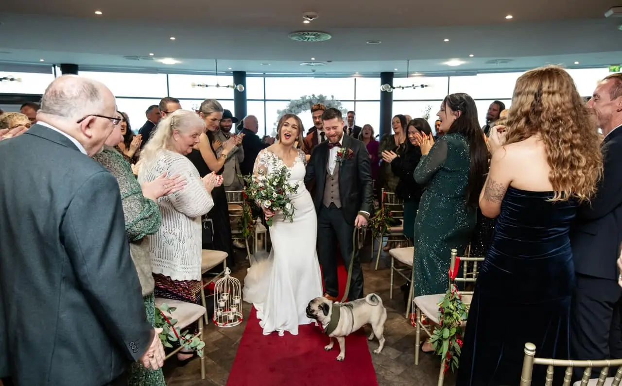 Bride and groom walking down the aisle with their pug at an Irish wedding ceremony